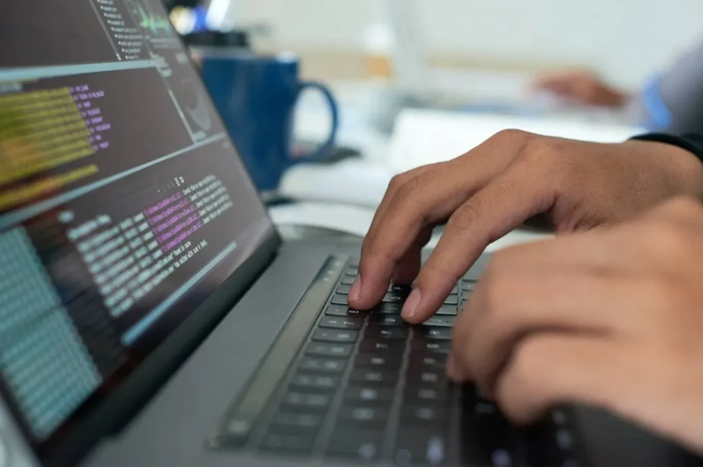 Programmer typing code on laptop keyboard