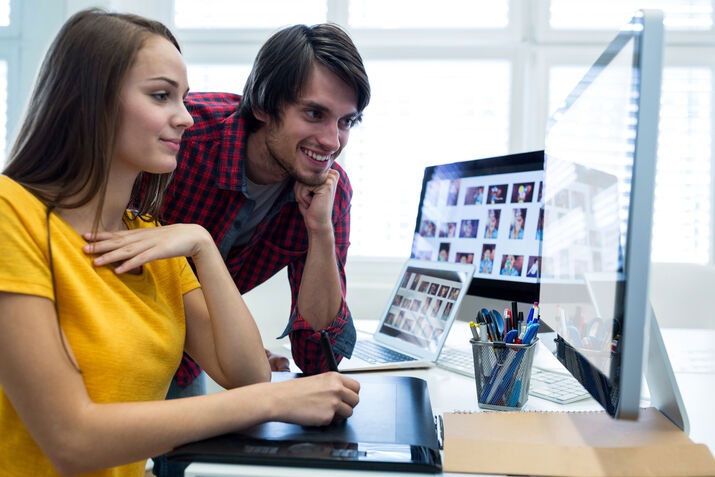 Creative designers reviewing responsive website design on desktop computers